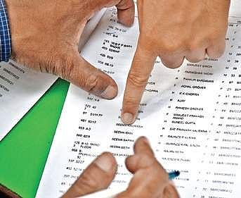 A voter checks the voters list at a polling station at Rajinder Nagar  on Sunday. | (Naveen Kumar | EPS)