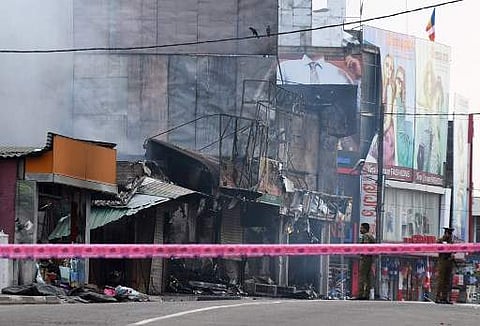 Sri Lankan police officers (R) stand near a damaged shop after a mob attack in Minuwangoda on May 14, 2019. (Photo | AFP)