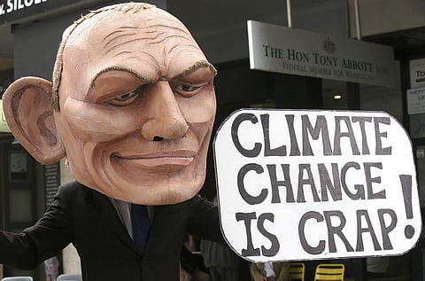 In this May 3, 2019, file photo, a demonstrator with a giant head in the likeness of former Australian Prime Minister Tony Abbott holds a sign referencing a comment by Abbott made in 2017 belittling the science of climate change, during a student organize