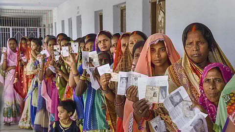 Women show their voter identity cards as they stand in a queue at a polling station. Representational image.