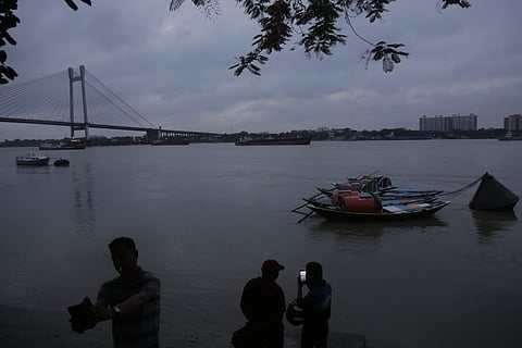 Country boats are seen moored as people look on at Hooghly river in Kolkata (Photo | AP)