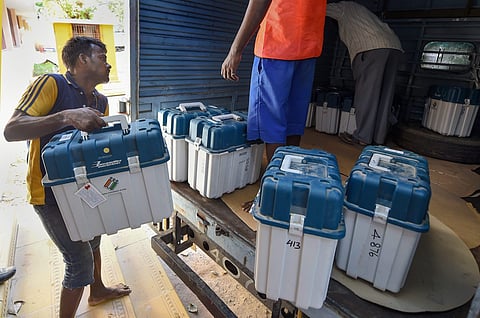 Workers carry boxes containing Electronic Voting Machines (EVM) and Voter Verified Paper Audit Trail machines (VVPATs) at a distribution centre. (File Photo | PTI)