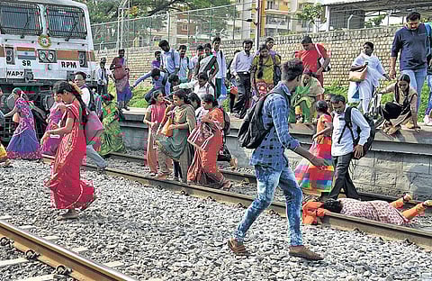 As passengers rush to catch their train at Whitefield Railway Station, a woman falls down on the tracks, on Saturday | NAGARAJA GADEKAL