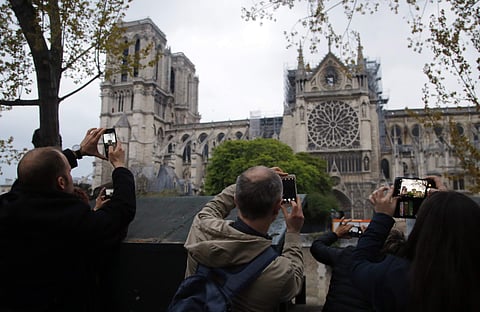 People take photos of the Notre Dame Cathedral in Paris, one day after a major blaze broke out at Paris' iconic cathedral (File photo | AP)