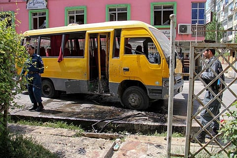 Afghan security personnel stand near the a damage bus carrying university students at the site of the successive bomb blasts in Kabul (Photo | AFP)