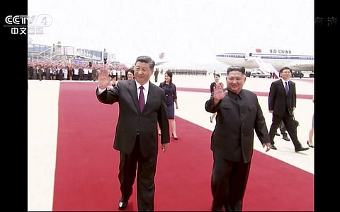 In this image taken from a video footage run by China's CCTV, Chinese President Xi Jinping, left, and North Korean leader Kim Jong Un, right, wave as President Xi arrived at an airport in Pyongyang, North Korea. (Photo | AP)
