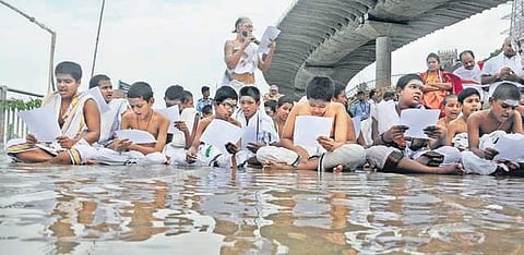 Students of Veda Pathasala chanting hymns during Varuna Yagam on the banks of Krishna river at Durga Ghat in Vijayawada on Thursday. (Photo | Prasant Madugula/EPS)