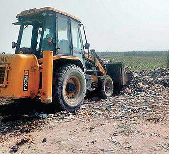A JCB works on cleaning debris from the Yamuna river belt