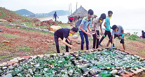 A group of youths make a pile of empty liquor bottles they collected from various tourist spots in Visakhapatnam on Friday. (Phtot | G satyanarayana/EPS)