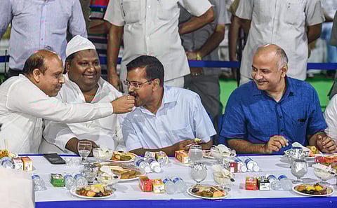 Delhi Chief Minister Arvind Kejriwal being offered a bite by BJP MLA Vijender Gupta as Deputy CM Manish Sisodia looks on at an Iftar party in New Delhi on 3 June 2019. (Photo | PTI)
