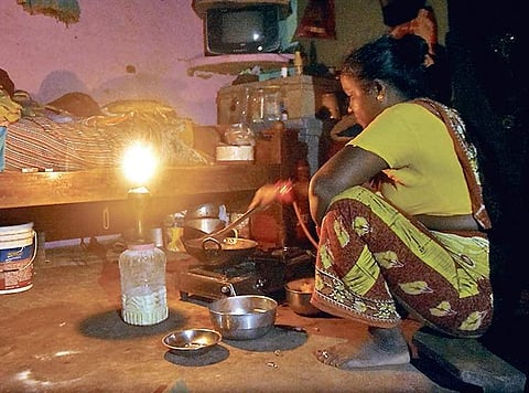 A woman cooks food in the light of kerosene lamp at Baliapanda slum in Puri on Sunday | Express