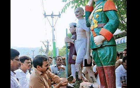 MLA Ramakrishna Reddy with the help of a mason fixes broken statue of Mahatma Gandhi at Polkampadu on Tuesday | EXPRESS