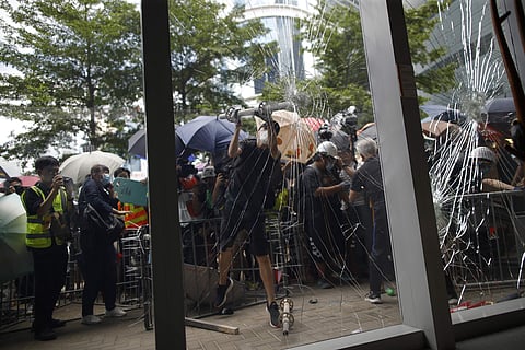 A protester tries to break the glass to get into the Legislative Council in Hong Kong. (Photo| AP)