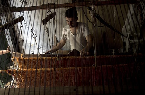 Palestinian worker weaves carpets on a traditional wooden loom at a carpets factory in Gaza City. (Photo | AP)