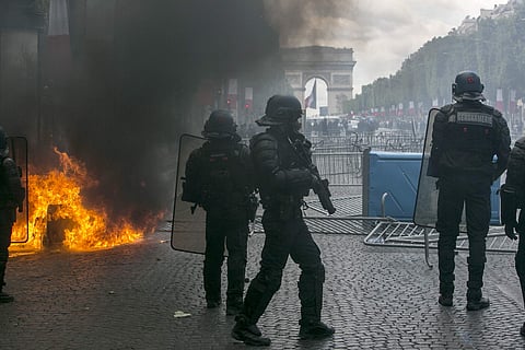 Riot police officers take position on the Champs-Elysees avenue during scuffles with demonstrators after Bastille Day parade in Paris (Photo | AP)