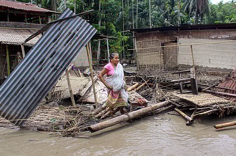 A woman stands near her damaged hut caused due to flooded area due to incessant rainfalls at Hajo in Kamrup on 13 July 2019. (Photo | PTI)