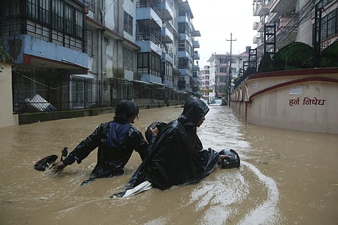 A Nepalese pulls his motorbike and wades past a flooded street in Kathmandu  | AP