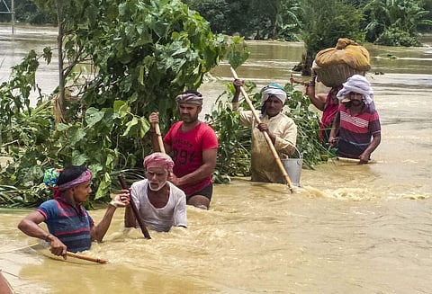 People cross a flooded street following incessant monsoon rainfall at Madhubani district Monday July 15 2019. | PTI