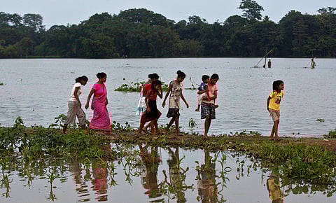 Villagers walk near flood waters in Jhargaon, east of Gauhati, Assam. (Photo | AP)