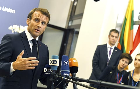 French President Emmanuel Macron, left, speaks with the media as he leaves after an EU summit in Brussels, Monday, July 1, 2019. European Union leaders continued marathon talks on Monday desperately seeking a breakthrough in a diplomatic fight over who sh