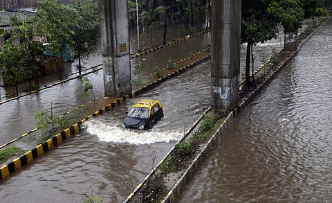 A car moves through a waterlogged street following heavy rains in following heavy rains in Mumbai. (Photo | AP)