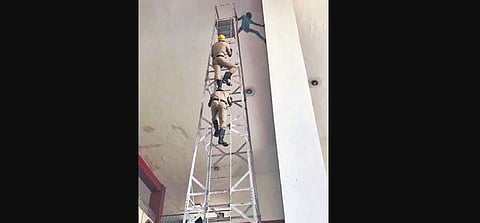 Fire department personnel climb up the ladder to rescue the man (Photo | EPS)