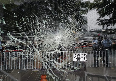 Police officers stand guard near a broken glass outside Legislative Council building in Hong Kong, Tuesday, July 2, 2019. Hundreds of protesters swarmed into Hong Kong's legislature Monday night, defacing portraits of lawmakers and spray-painting pro-demo