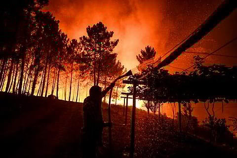 A villager holds a hose as a wildfire comes close to his house at Amendoa in Macao, central Portugal on July 21, 2019. More than a thousand firefighters battled to control wildfires in central Portugal that have forced village evacuations, in a region whe