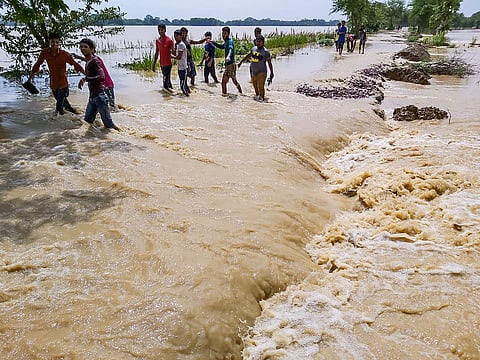 People cross a flooded street that caved in following incessant monsoon rainfall at Madhubani district in Bihar. (Photo| PTI)