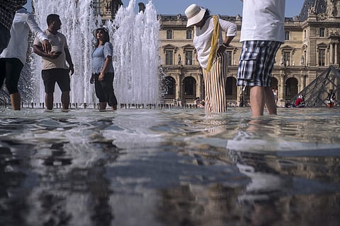 People cool off next to the fountains at Louvre Museum in Paris, France. (Photo | AP)