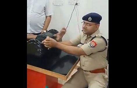 A UP policeman gives foot massages to a kanwariya (devotee of Lord Shiva). (Videograb)