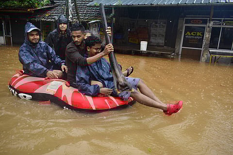 People using a small raft to cross Moozhikal in Kozhikode which submerged in flood water. | (Manu R Mavelil | EPS)