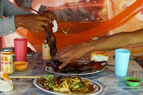 Customers eating grilled rats at a stall in Battambang province. Barbecued field rats are not everybody's idea of a tasty treat, but in Cambodia's rural Battambang province they are popular as a cheap - and quick - snack, with small skewered ones going fo