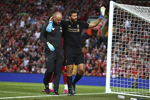 Liverpool's goalkeeper Alisson Becker, right, waves to the fans as he leaves the pitch after an injury. (Photo | AP)
