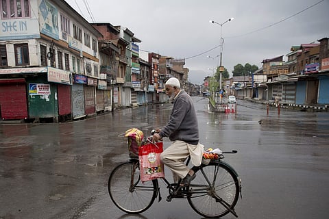 A Kashmiri man rides a bicycle through a deserted street during security lockdown in Srinagar Wednesday August 14 2019. | AP