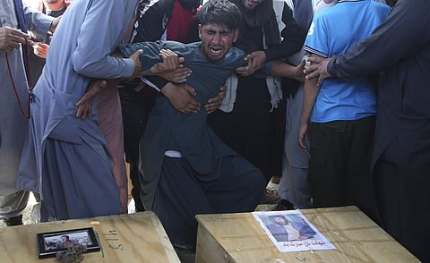 A relative wails near the coffins of victims of the Dubai City wedding hall bombing during a mass funeral in Kabul, Afghanistan. (Photo | AP)