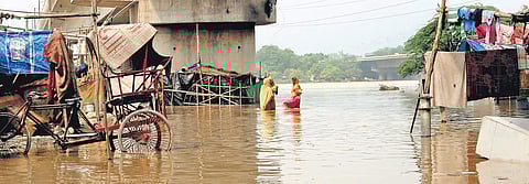 Residents busy doing everyday chores in a flooded locality along the banks of river Yamuna after its water level rose following release of water from the Hathinikund Barrage, in New Delhi| Arun Kumar
