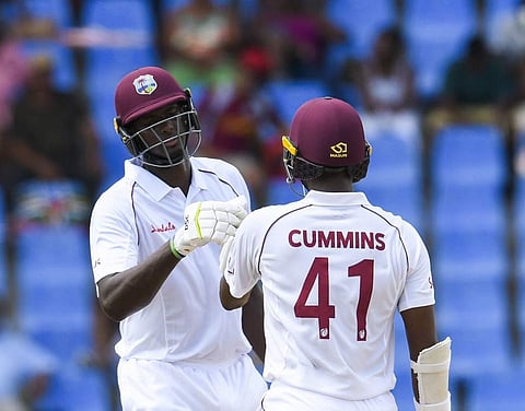 Jason Holder (L) and Miguel Cummins (R) of West Indies partnership during day 3 of the 1st Test between West Indies and India at Vivian Richards Cricket Stadium in North Sound, Antigua and Barbuda. (Photo | AFP)