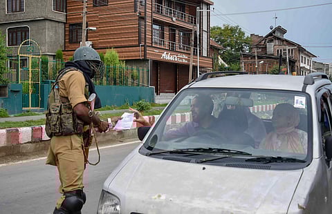 A security person checks the movement-pass of man at a check-point during curfew like restrictions on the 13th consecutive day following the abrogation of the provisions Article 370 in Jammu and Kashmir in Srinagar Saturday August 17 2019. | PTI
