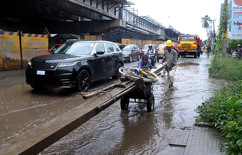 KSEB officials struggling to shift an electricity post through waterlogged Kundannoor Junction | A Sanesh