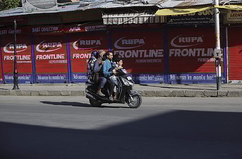 A Kashmiri family rides on a scooter past a closed market in Srinagar (File | AP)