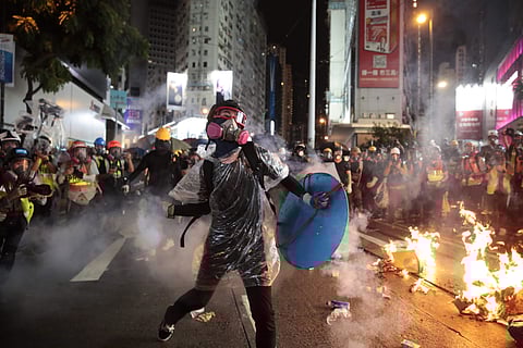 A protestor hurls back an exploded tear gas shell at police officers in Hong Kong on Saturday (Photo | AP)