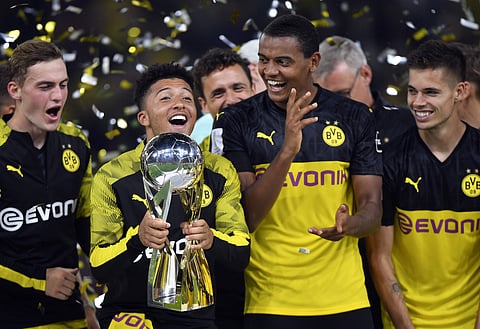 Borussia Dortmund's Jadon Sancho lifts up the trophy as he celebrates with teammates after winning the German Super Cup final match against Bayern Munich in Dortmund. (Photo | AP)