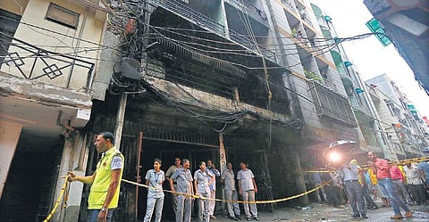 Police stand at the spot where a fire broke out in a residential building at Zakir Nagar in south-east Delhi. (Photo | Arun Kumar)