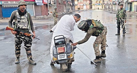 Soldiers check the bag of a man riding a scooter during strict restrictions in Srinagar on Thursday | PTI