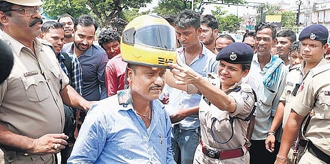 Traffic DCP Sagarika Nath gifting a new helmet to a commuter after collecting fine from him for violating traffic rules at Kalpana Square on Tuesday (Photo | EPS,Irfana)