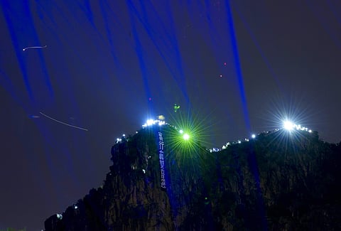 Demonstrators hold up the mobile phone lights and laser pointer as they gather on the Lion Rock mountain against the night view of Hong Kong.  ( Photo | AP )