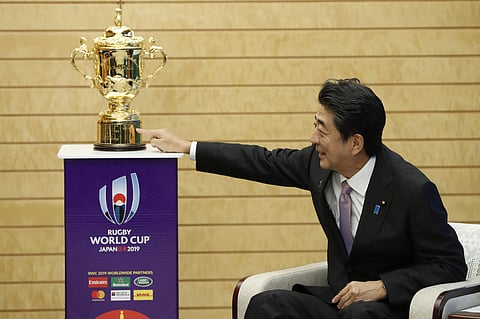 Japan's Prime Minister Shinzo Abe points to the Webb Ellis trophy during a courtesy call by World Rugby officials as part of the trophy tour ahead of the Rugby World Cup, at Abe's official residence in Tokyo. (Photo | AP)