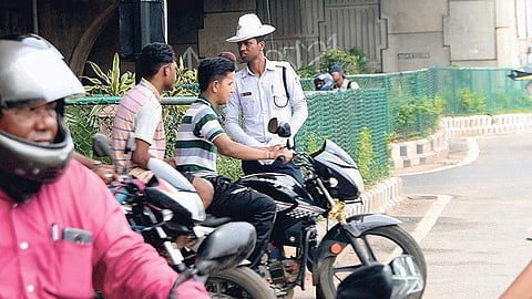 A biker driving without helmet in front of a traffic personnel. (Photo| EPS)