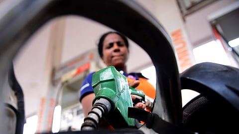 An employee at a petrol bunk fills fuel in a vehicle.